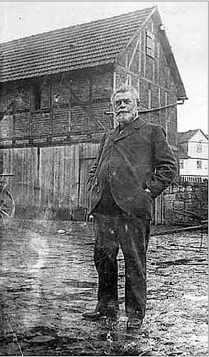 Bauer Ludwig Förster steht auf seinem Hof in Waldau, im Hintergrund sein Gebäude