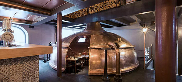 Innenräume Sudhaus nach Umbau, Kupferkessel mit Stühlen und Tischen