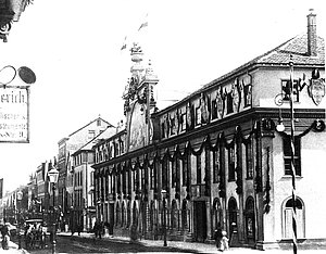 Messehaus am Carlsplatz um 1900, Häuserfront davor Personen und Pferdekutsche