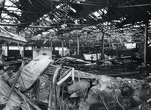 Trümmer einer zerstörten Werkshalle, offenes Dach und verbogene Stahlträger 