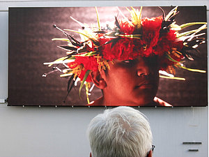 Ein Mann betrachtet eine Videoinstallation zur d15 auf der Außenwand der Firma Hübner
