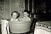 Zwei Kinder sitzen in der Zinkbadewanne im Wohnraum
