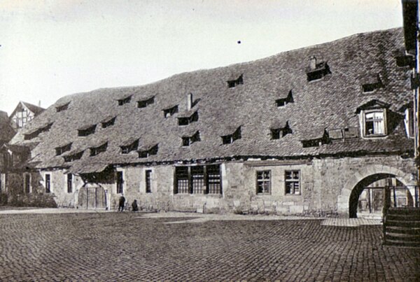 Mühle vom Mühlenplatz mit Sicht auf zwei Tore in der großen Sandsteinmauer des Gebäudes