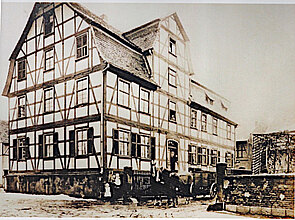 Wohnhaus und Hof Winkelstern, Kasseler Str. 28, auWohnhaus und Hof Winkelstern, Kasseler Str. 28 aus dem Fachwerkhaus schauen die Leute aus dem Fenster, davor stehen personen auf der Straße