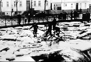 Kinder stehen mit Stöcken auf Eisschollen der Losse am Dorfplatz