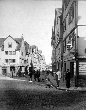 Alte Häuser, gepflasterte Straße und Männer, die den Photografen anschauen