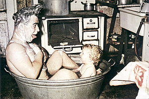 Vater und Sohn sitzen in einer Zinkwanne in der Küche, 1956