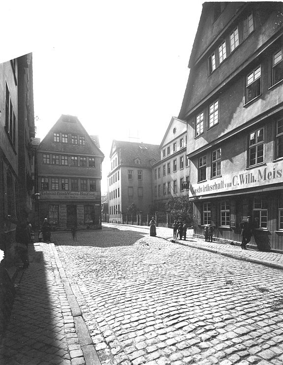 Entlang des Kopfsteinpflasters der Bettenhäuser Str. geht der Blick auf das Waisenhaus, am rechten Rand sieht man ein Gasthaus 