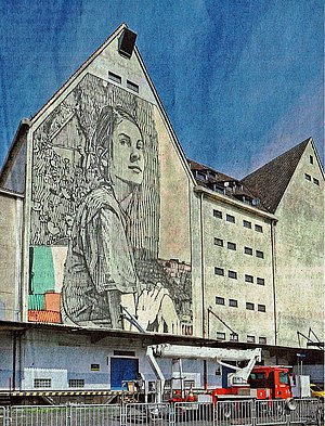 Fassade mit Portiat einer Frau und davor auf der Straße roter Hubsteiger