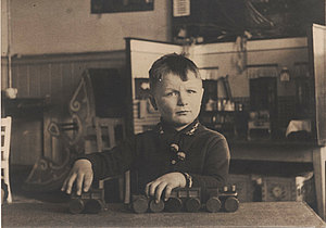 Karl Wils spielt mit einer Holzeisenbahn auf dem Tisch im Kindergarten 1937