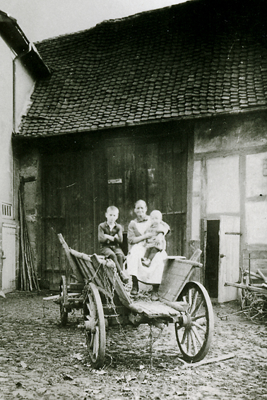 In der Buttlarstraße 6 sitzt 1924 Großmutter Schweitzer mit zwei Enkeln auf dem Leiterwagen 