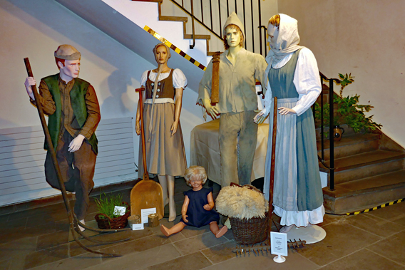 Mittelalterlich gekleidete Schaufensterpuppen mit zeitgemäßen Geräten 