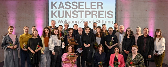 Große Gruppe der Preisträgerinnen 2022 vor einem Plakat "Kasseler Kunstpreis"
