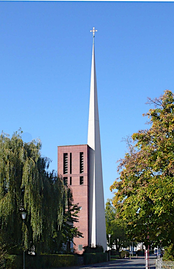 Dreieckige weise Kirchturmspitze neben rotem Glockenturm 