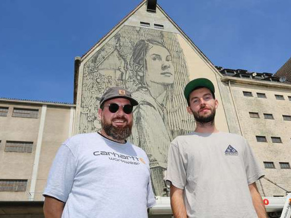 Die Künstler Dustin Schenk (links) von Kolorcubes und Street-Art-Künstler Sainer. vor dem Bild an der Hafensilowand 2019