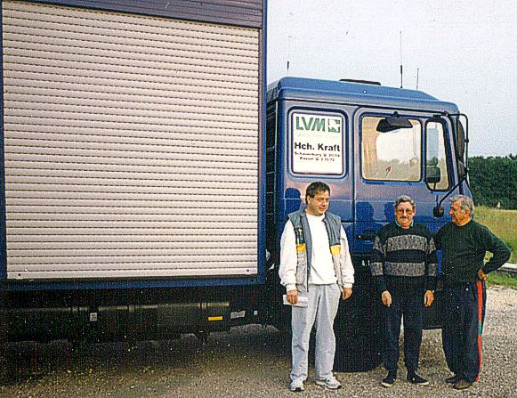 Drei Münner stehen vor dem Transport-LKW für Tauben