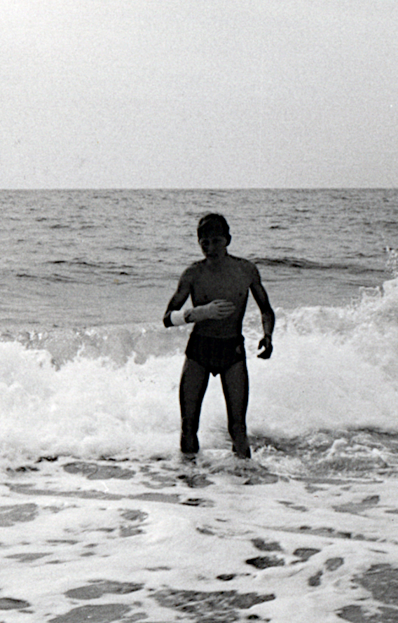 Junge mit Gipsarm in den Wellen auf Sylt 