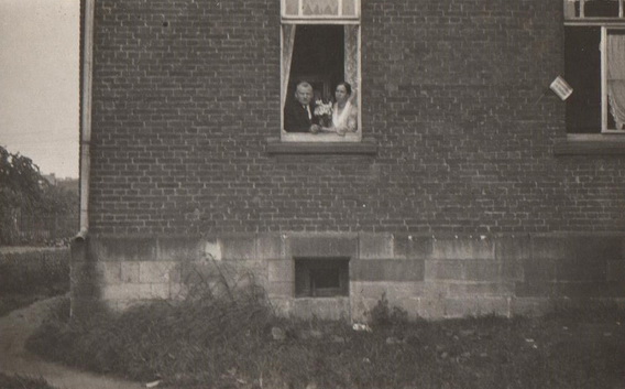 Oma und Opa schauen aus dem Wohnzimmerfenster in den Hof 