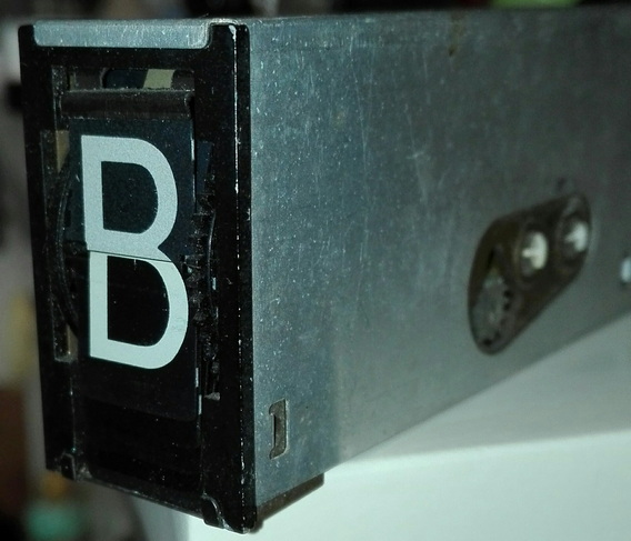 Ein rechteckiges kleines Metallgehäuse zeigt ein B an. Ein Schaltwerk zur Bestückung der Anzeigetafel 
