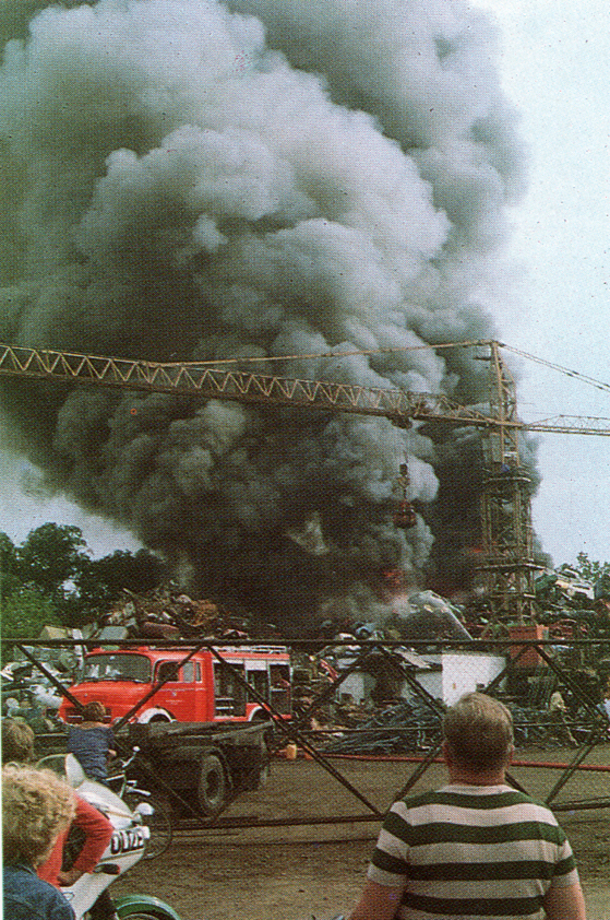 Schaulustige stehen am Zaun der Brandstelle 