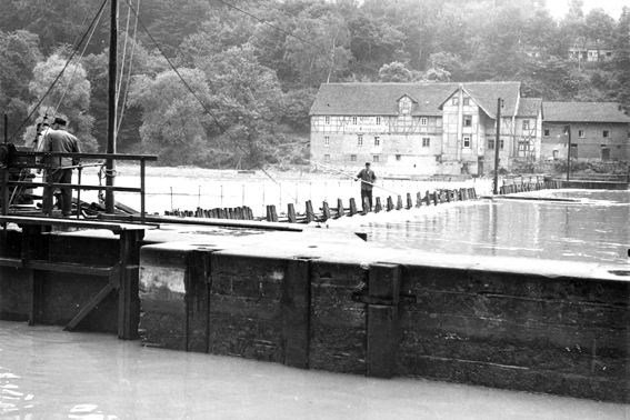 Blick über Schleuse und Wehr nach Spiekershausen, zwei Männer auf der Schleusenmauer 