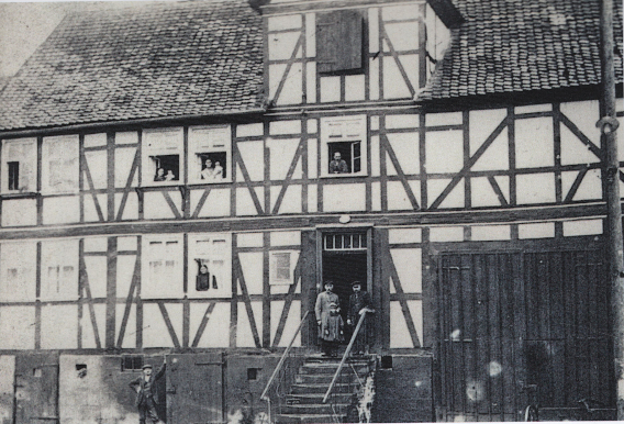 Aus dem Fachwerkhaus Brede Nürnberger Str. 160160 schauen Personen aus dem Fenster und die Famile steht auf der Treppe vor der Tür